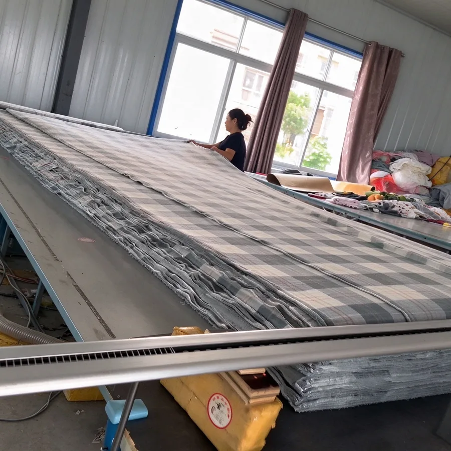 Worker spreading plaid fleece fabric on the long cutting table