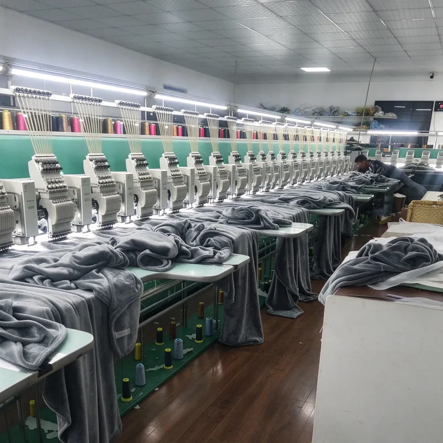 Row of multi-head embroidery machines working on gray fleece blankets