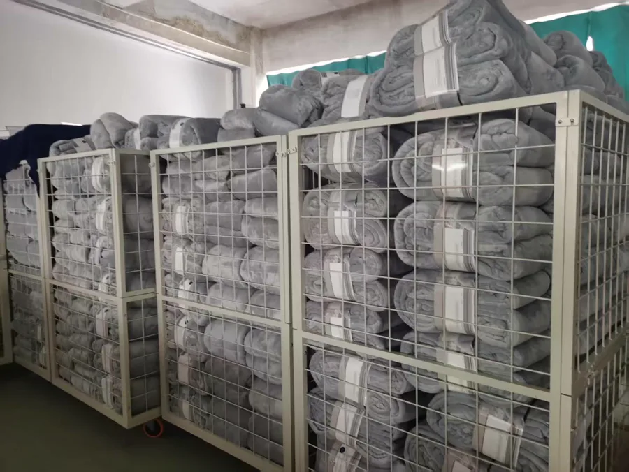 Roll-packed gray blankets stored in wire transfer cages between workshops