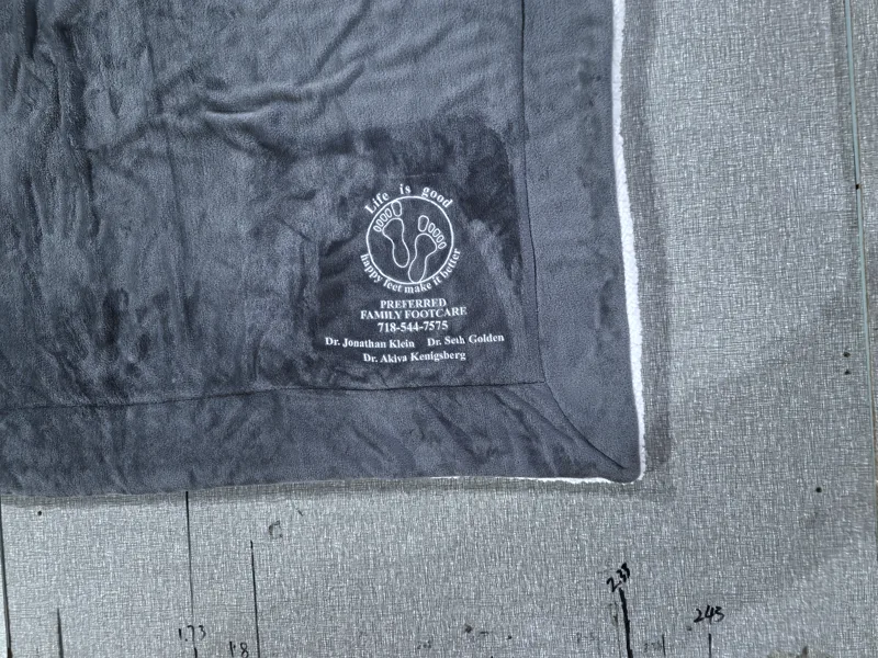 White fine-text logo heat transferred on dark navy sherpa blanket
